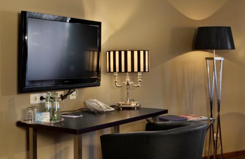 a room with a tv and a desk with a phone at Tryp by Wyndham Luebeck Aquamarin in Lübeck