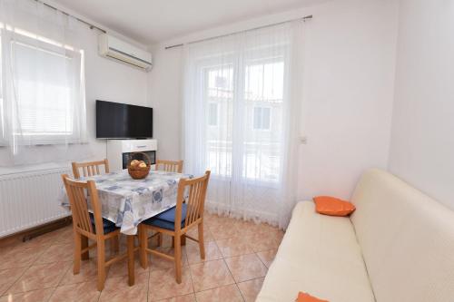 uma sala de jantar com mesa e cadeiras e uma televisão em Apartments Brico em Primošten