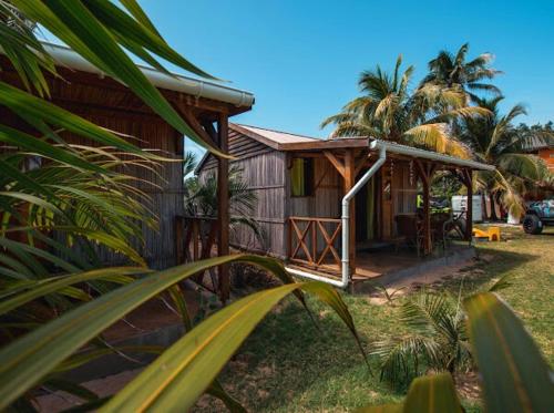 een klein houten huis met een veranda en palmbomen bij Gravier beach house in Rodrigues Island