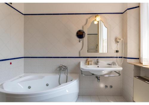 a bathroom with a white tub and a sink at Phi Hotel Canalgrande in Modena