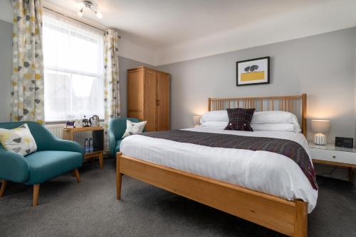 a bedroom with a large bed and a blue chair at Bodnant Guest House in Llandudno