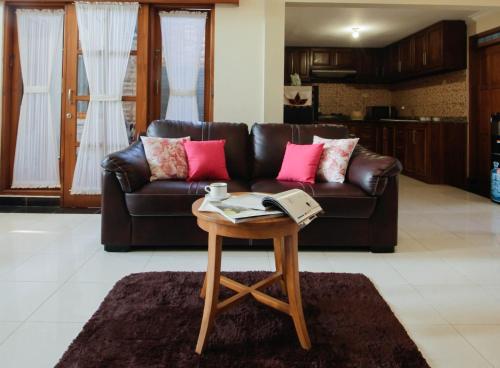 uma sala de estar com um sofá de couro castanho e uma mesa em Nginap at Joy House em Sleman
