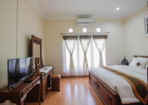a bedroom with a bed and a flat screen tv at Nginap at Joy House in Sleman