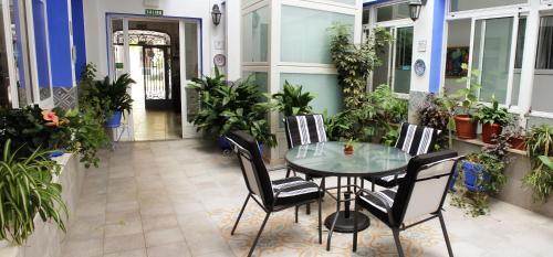 un patio con mesa de cristal, sillas y plantas en Pensión Guerrero en Cabra