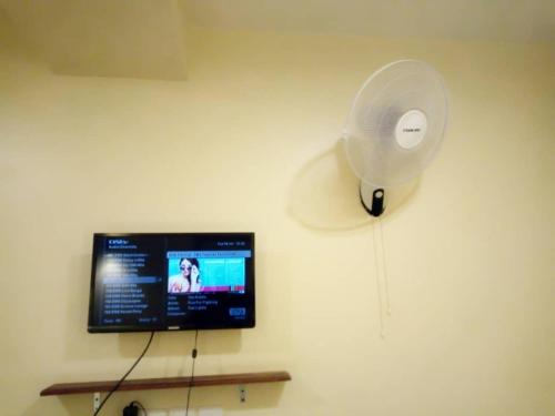un ventilador blanco y una TV en la pared en Shangri-La Fortune Hotel en Kampala
