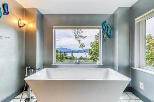 a large white tub in a bathroom with a window at 6 Bed 4 Bath Vacation home in Eastsound in Eastsound