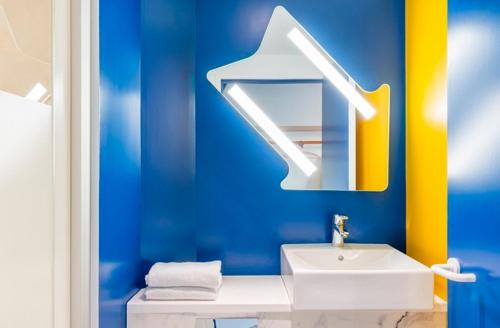 La salle de bains bleue est pourvue d'un lavabo et d'un miroir. dans l'établissement Ibis Budget Montpellier Nord Euromédecine, à Montpellier