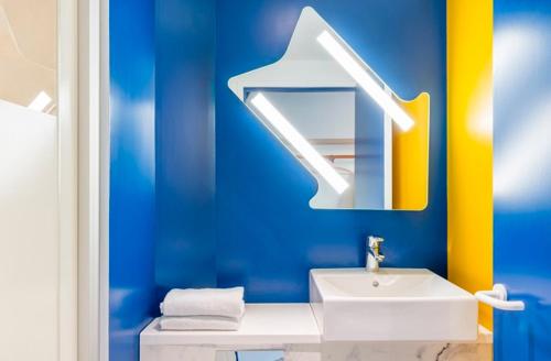 a blue bathroom with a sink and a mirror at Ibis Budget Montpellier Nord Euromédecine in Montpellier