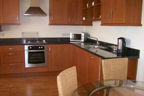 a kitchen with wooden cabinets and a table with a microwave at Contemporary Cottage Holidays in Bridlington