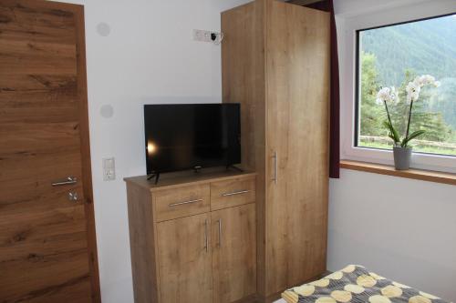 a room with a tv on a cabinet with a window at Haus in der Kurve in Kappl