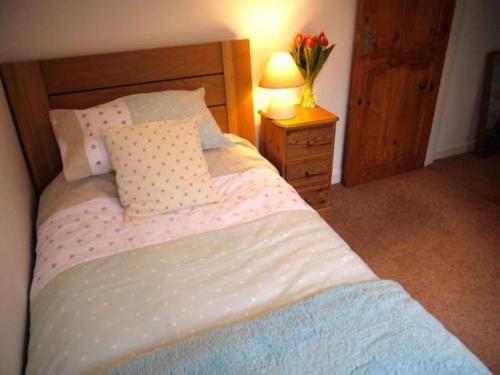 a bedroom with a bed and a vase of flowers on a night stand at Jimmer's Loft in Cadgwith