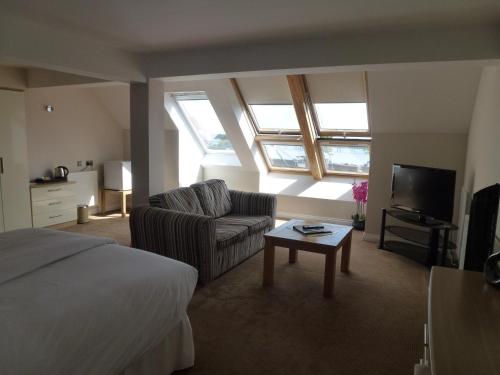 a bedroom with a bed and a couch and a tv at Boathouse Hotel in Hythe