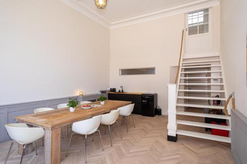 a dining room with a wooden table and white chairs at Sleep&Stay Floris IV in The Hague