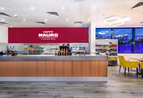 a coffee mauo counter in a restaurant with tables and chairs at Atrium Hotel Heathrow in Hillingdon