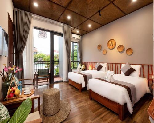 ホイアンにあるTropical Home Villaのベッド2台とリビングルームのある寝室
