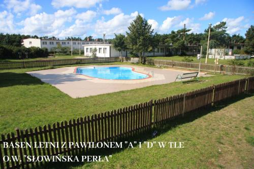 a swimming pool in a yard with a fence at Słowińska Perła in Rowy
