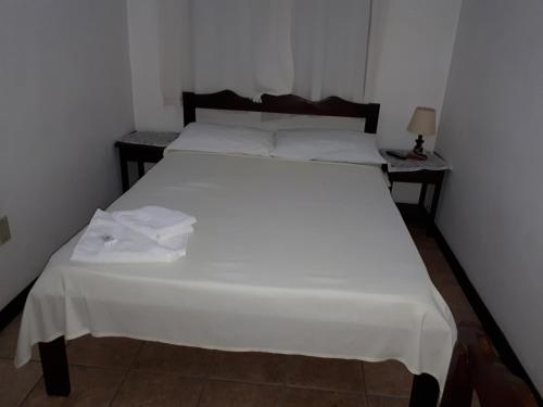 a white bed in a room with two tables at Schulz Pousada in Joinville