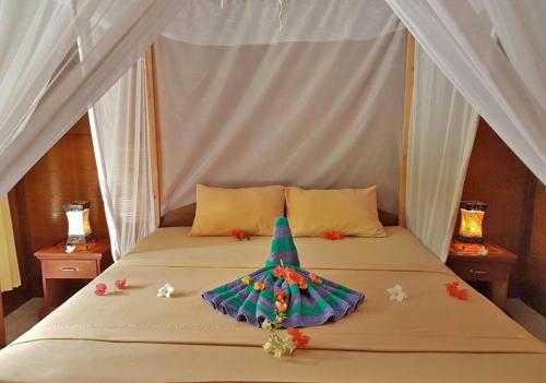 a bed with a christmas tree on top of it at Colour Cottage in Gili Air