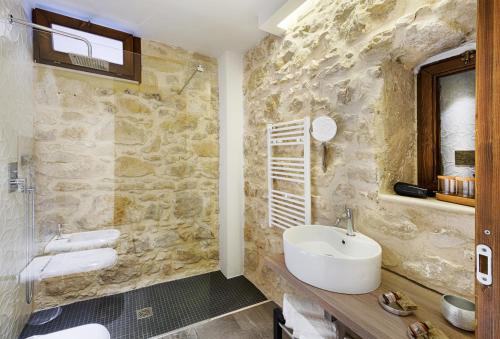 baño con lavabo y pared de piedra en Centosedici Rooms, en Ragusa