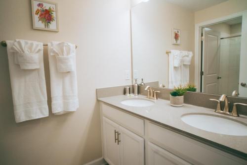 La salle de bains est pourvue de 2 lavabos, d'un miroir et de serviettes. dans l'établissement Luxury Townhouse with private pool, à Kissimmee