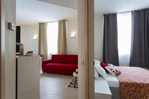 Cette chambre comprend un lit et un canapé rouge. dans l'établissement Casa Vermiglio al porto di Genova by Wonderful Italy, à Gênes