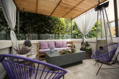 a patio with purple chairs and a purple couch at Hotel Villa Condesa in Mexico City