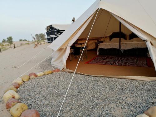 a tent on the beach with a bed in it at Al Reem Desert Camp in Jalan Bani Buhassan