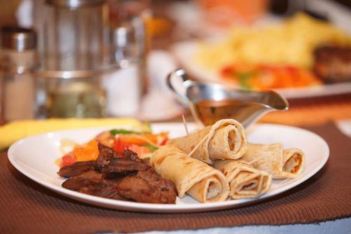 a plate of food with meat and pasta on a table at Shangri-La Fortune Hotel in Kampala