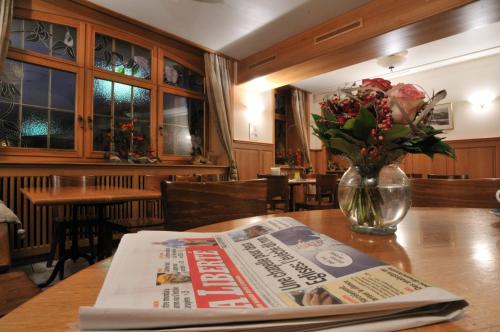 a newspaper on a table with a vase of flowers at Hôtel Restaurant Cave Bel-Air in Praz