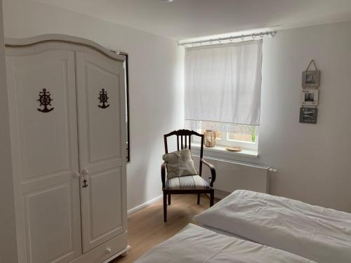 a bedroom with a bed and a chair and a window at Haus Vicus in Greifswald