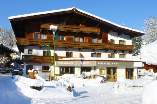 ein großes Gebäude mit Schnee davor in der Unterkunft Hotel Feichter in Söll