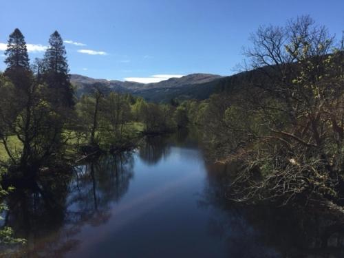 a view of a river with trees on the side at Sir Andrew Murray House in Strathyre