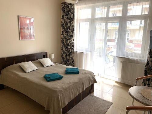 a bedroom with a bed with two blue towels on it at Apartamenty Trzy Korony in Świnoujście