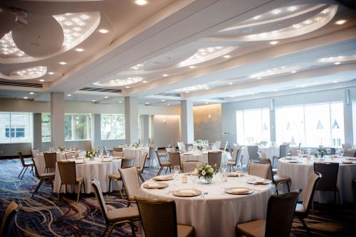 um salão de banquetes com mesas e cadeiras brancas em The Statler Hotel at Cornell University em Ithaca