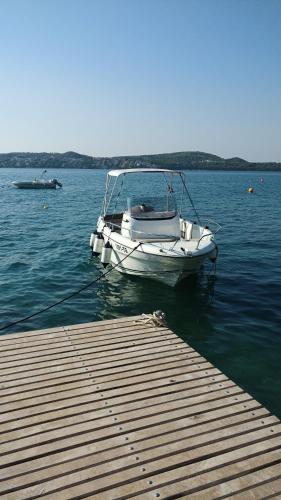 a boat sitting on the water next to a dock at Secret Garden Barada Beach Apartment in Trogir