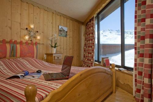 1 dormitorio con 1 cama con ordenador portátil en Résidence Le Portillo en Val Thorens