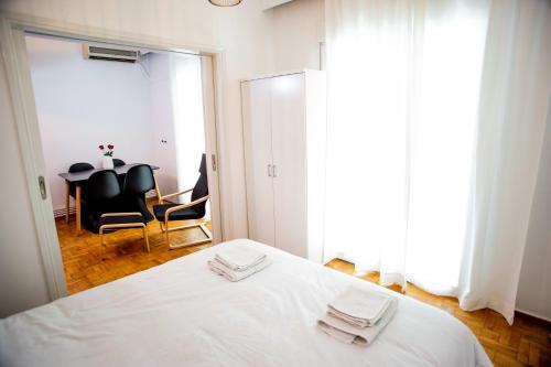 a bedroom with a white bed and a table and chairs at Thessaloniki Center Apartment On The Sea in Thessaloniki