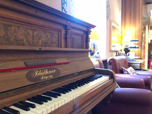 a piano in a living room with a couch and chairs at Hotel Rovereto in Rovereto