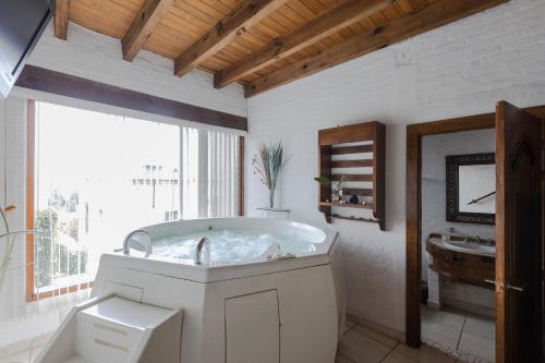 a white bathroom with a tub and a sink at Casa de la Loma in Morelia