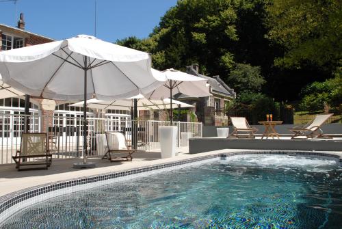 una piscina con sombrillas, sillas y una mesa en Domaine de Joinville, en Eu
