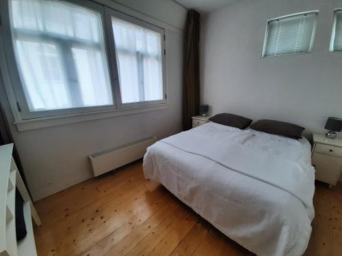 a bedroom with a white bed and two windows at Bickersbed in Amsterdam