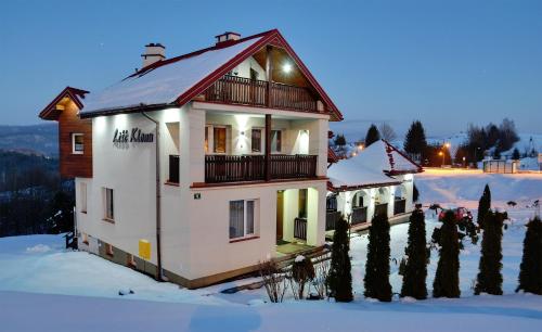 a large white house in the snow in the winter at Liść Klonu in Polańczyk