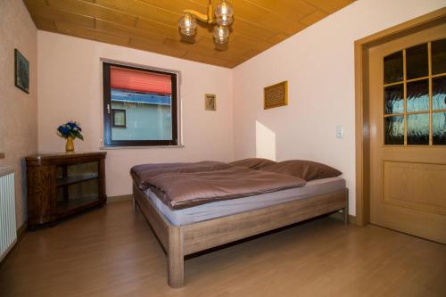 1 dormitorio con cama, ventana y puerta en am Balkon des Erzgebirges, en Bernsbach