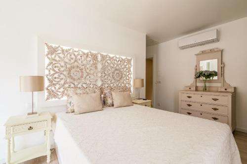 a white bedroom with a white bed and a dresser at Casa da Varanda in Ribafria
