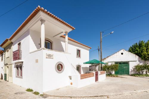 a white house with a green door at Casa da Varanda in Ribafria