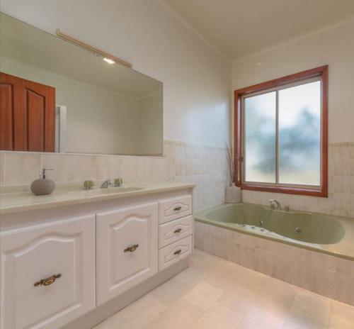 a bathroom with a tub and a sink and a mirror at Beltie Park Homestead in Wangaratta