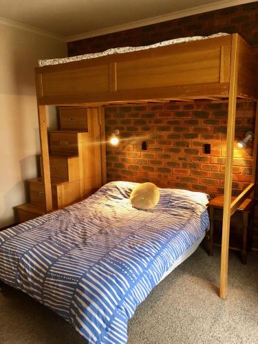 a bedroom with a bunk bed and a brick wall at Beltie Park Homestead in Wangaratta
