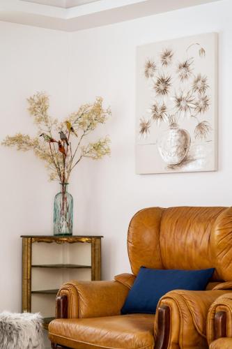 a living room with a leather couch and a vase with flowers at Casa da Varanda in Ribafria