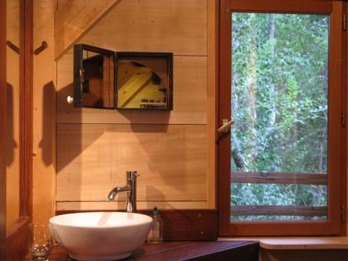 ein Badezimmer mit Waschbecken und Spiegel an der Wand in der Unterkunft Les Cabanes du Tertre in Urval