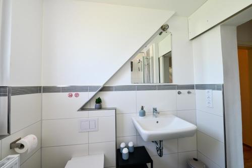 a white bathroom with a sink and a mirror at MIA - Ferienwohnung Wehdel bei Bremerhaven in Wehdel